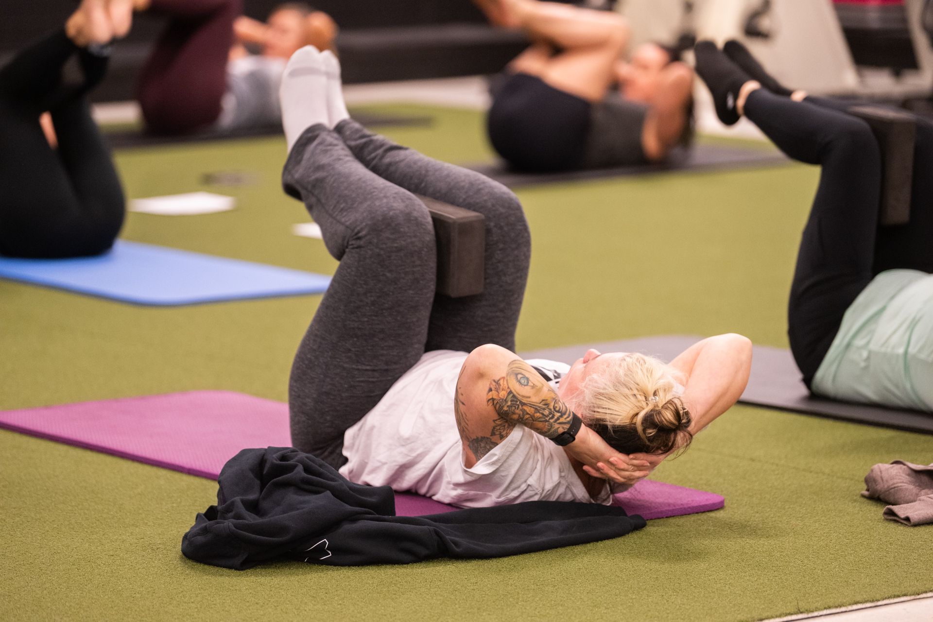 A group of people are doing exercises on yoga mats in a gym.