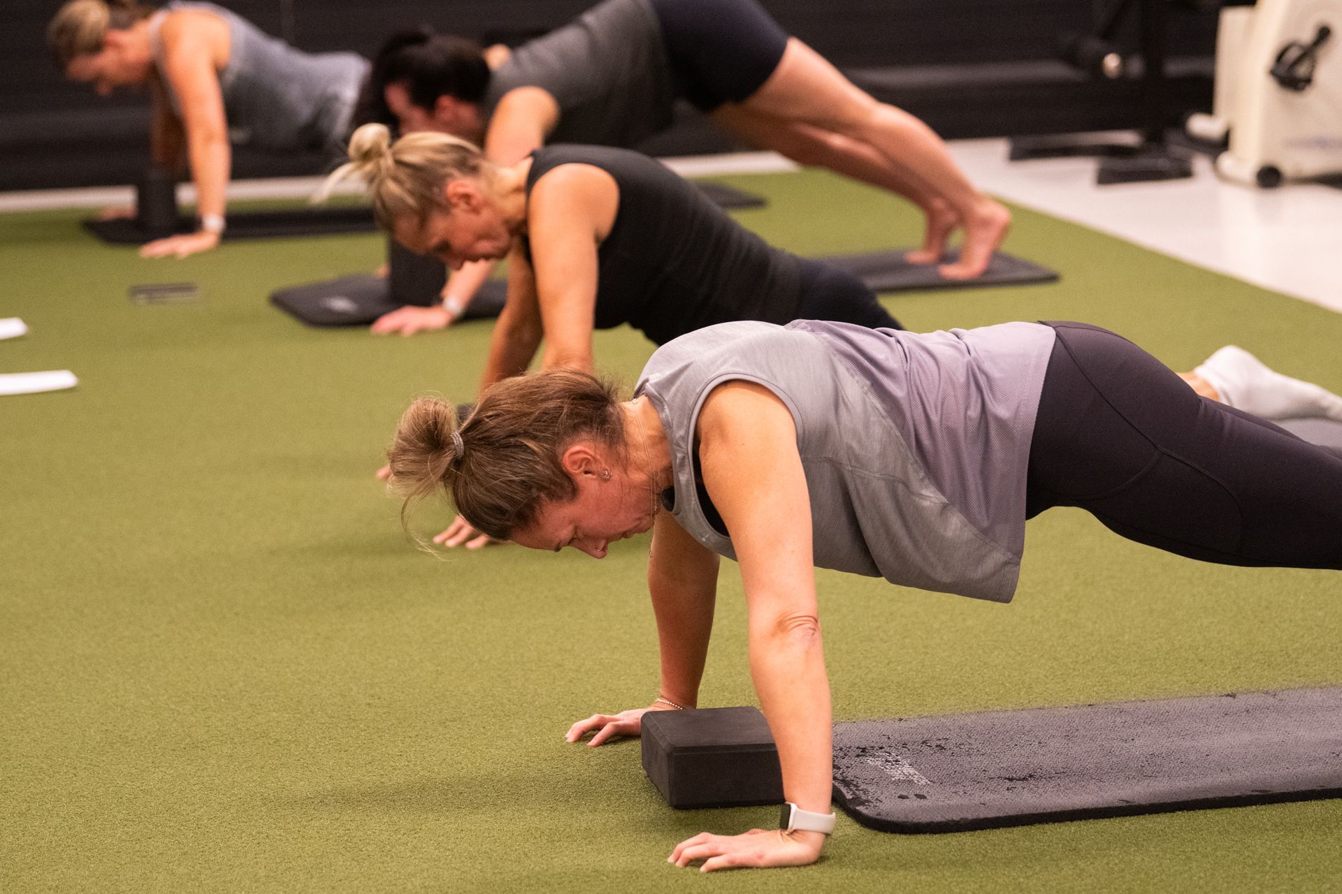 A group of women are doing push ups on yoga mats in a gym.