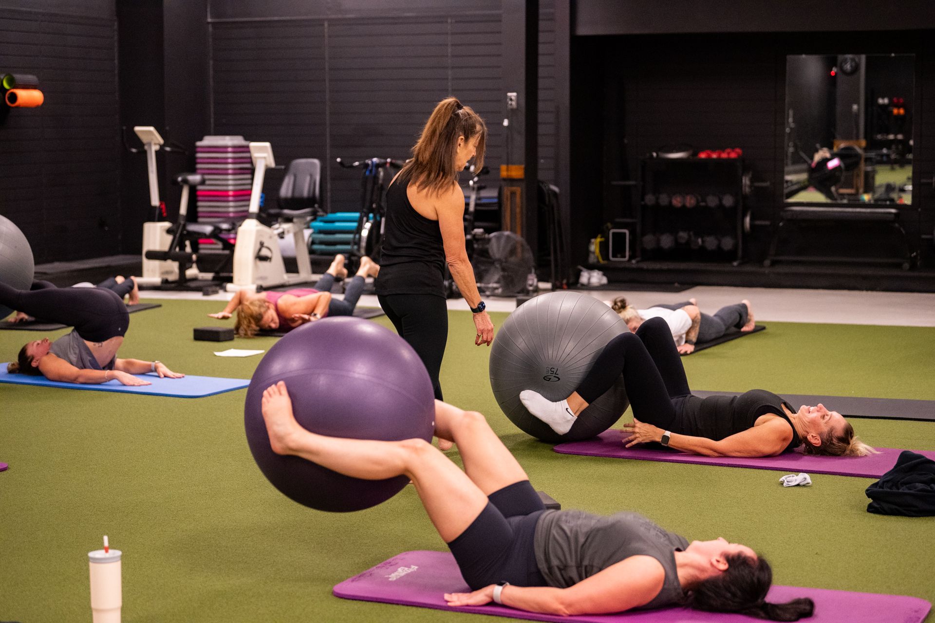A group of women are doing exercises with exercise balls in a gym.