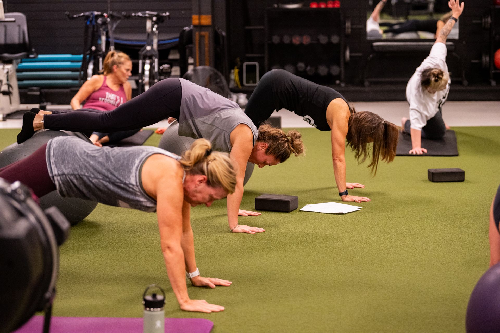 A group of women are doing push ups in a gym.