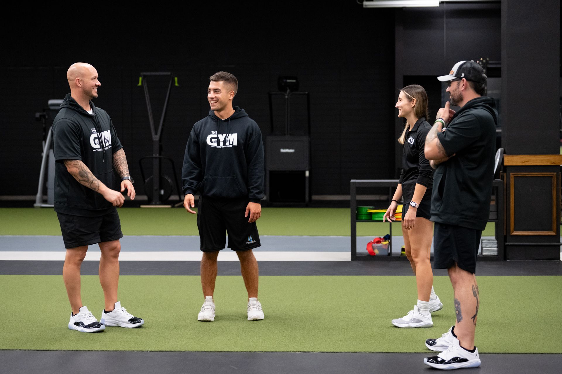 A group of people are standing in a gym talking to each other.