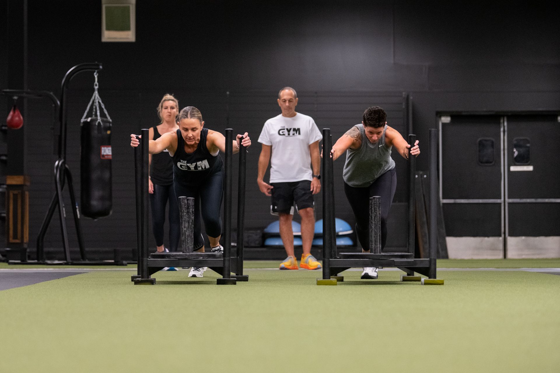 A group of people are pushing sleds in a gym.