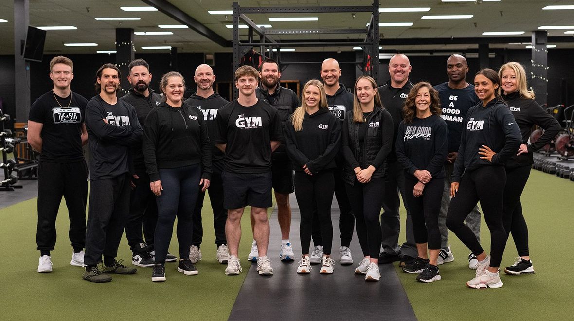 A group of people are posing for a picture in a gym.