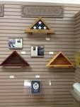 Display of wooden American flag cases and photos on a slat wall.