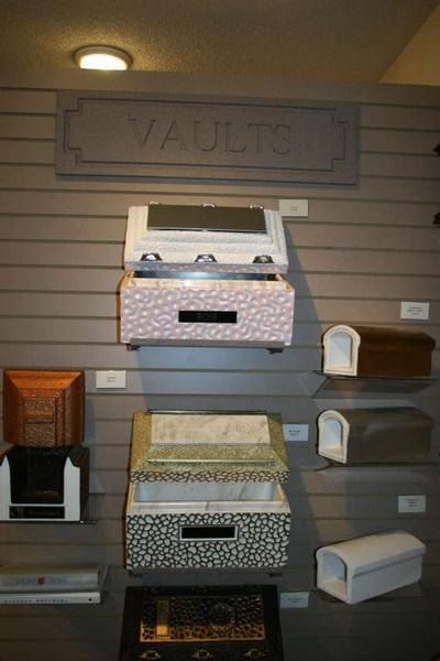 Display of burial vaults in various colors and designs, labeled 