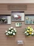 Wall display with floral arrangements, framed photos, and a sign.