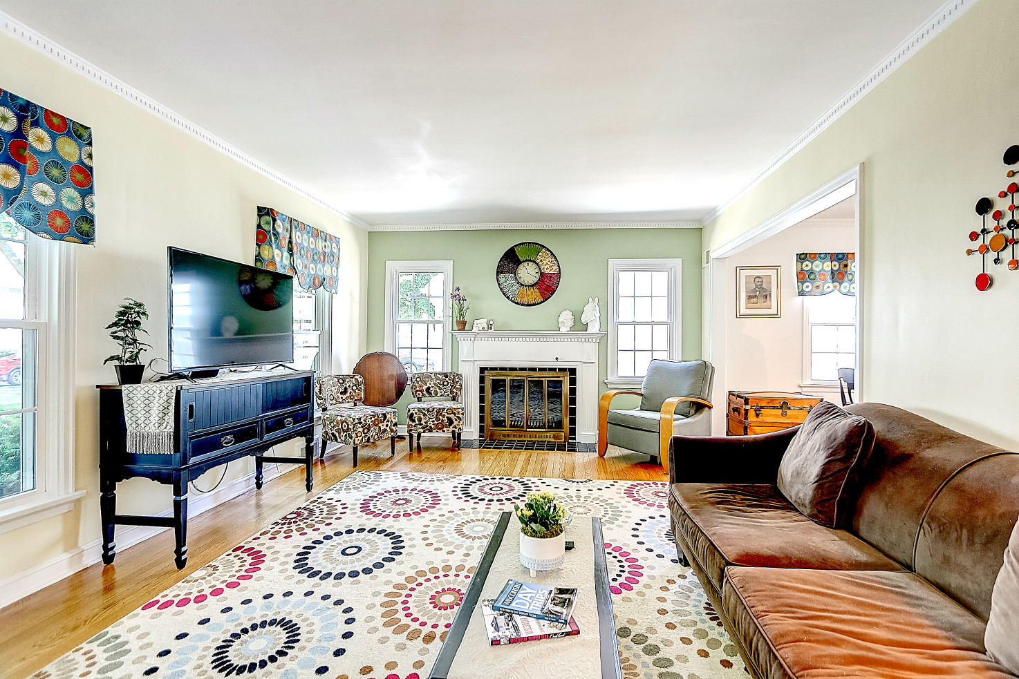 Living room with wooden floors, fireplace, and colorful patterned rug.