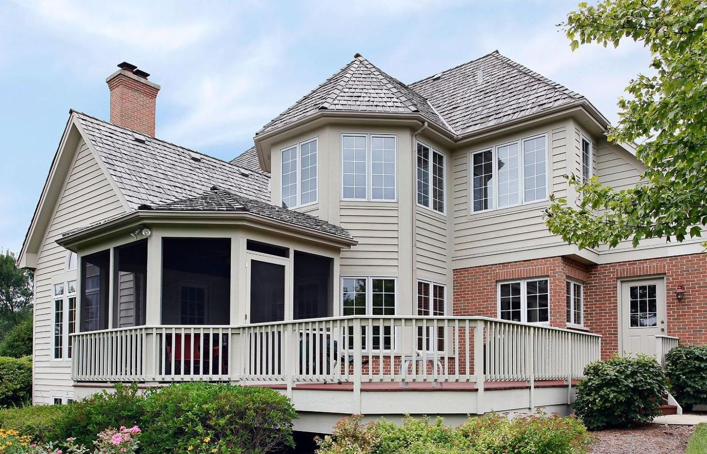 A large house with a screened in porch and a large deck