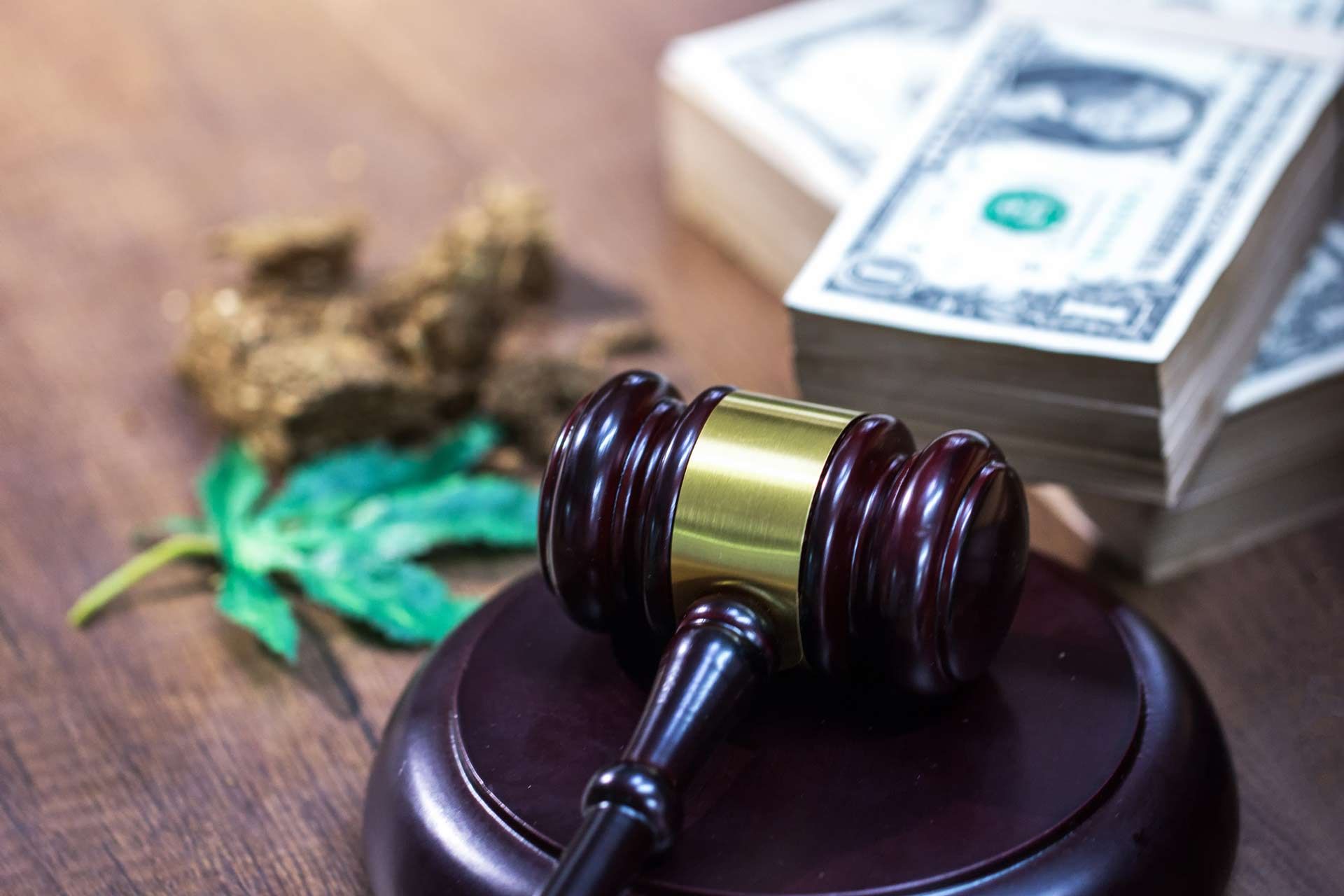 Judge hammer on top of a table, with a blurred cannabis leaf and stacks of money in the background - Santa Rosa, CA - The Law Office of Jonathan B. Steele 
