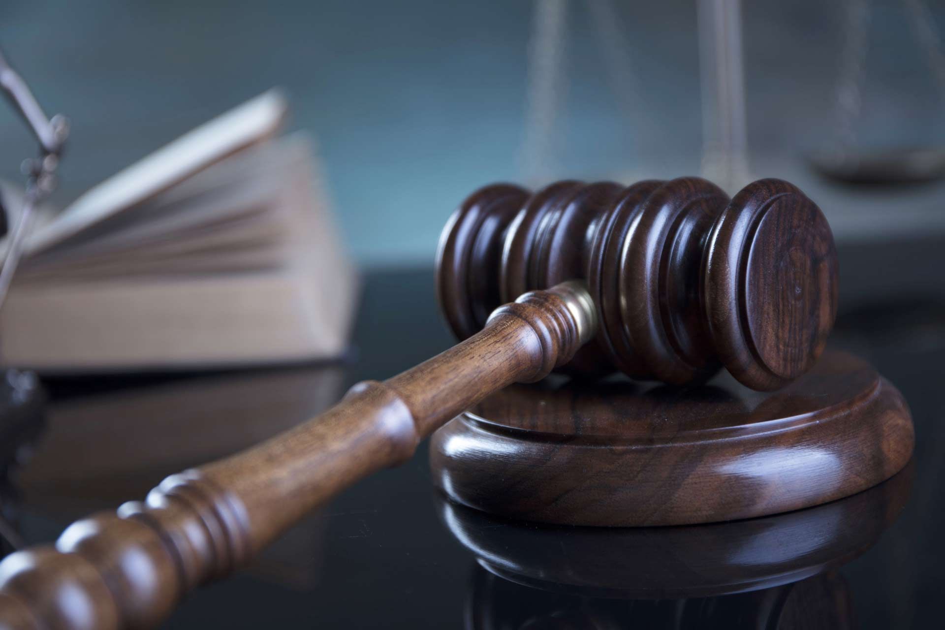 Close-up of a judge’s gavel and sound block on top of a table, with blurry books on the back - Santa Rosa, CA - The Law Office of Jonathan B. Steele 