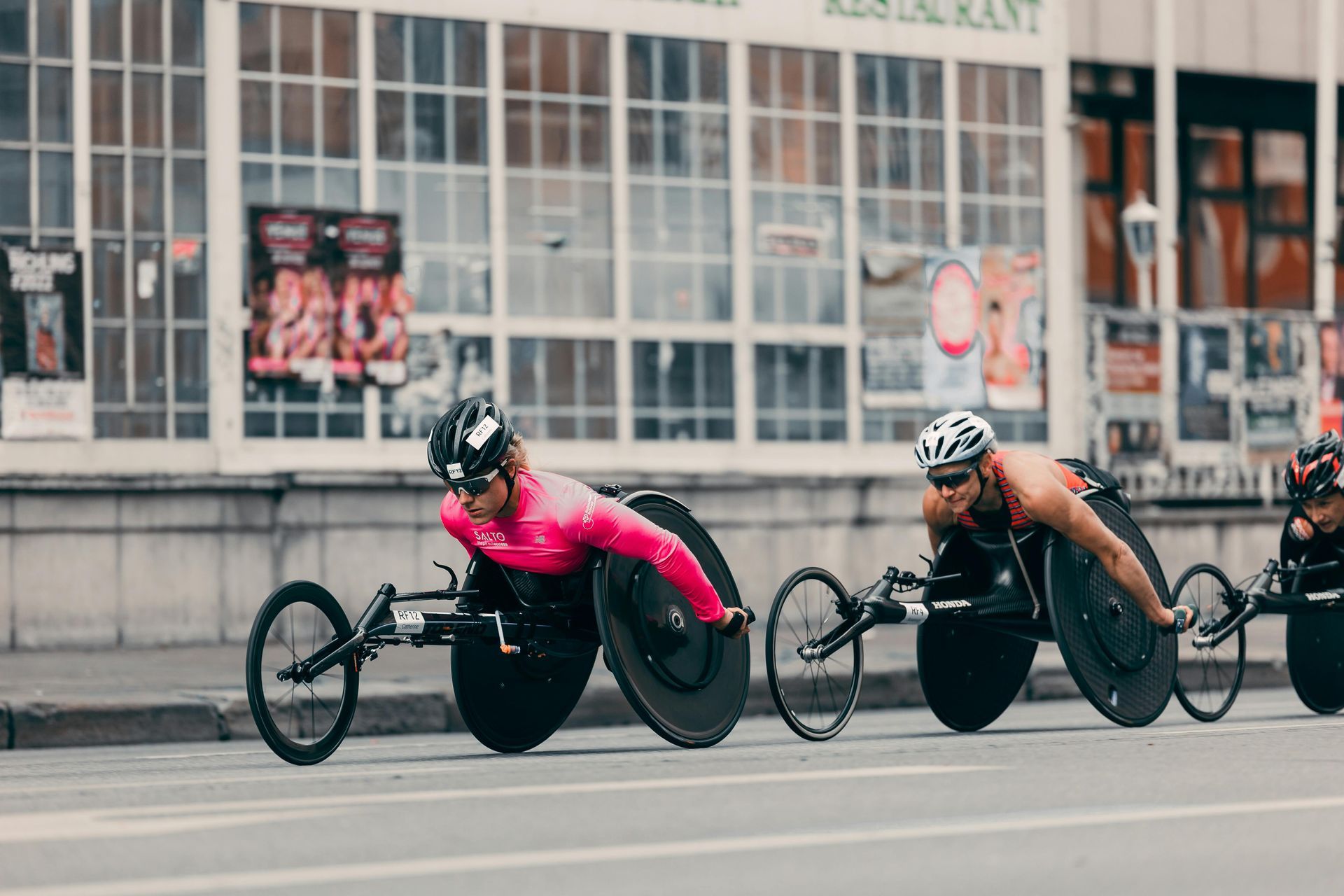 Wheelchair racers in a city street race.