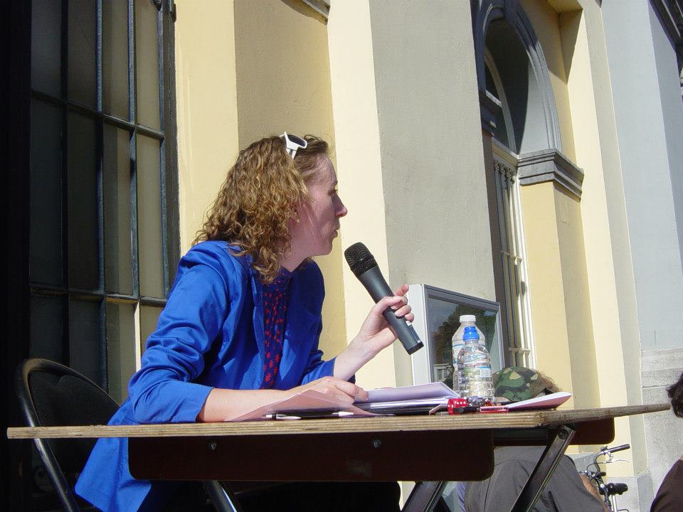 In 2012 had Susanne nog lang, krullend haar en werkte ze met een losse handmicrofoon voor de audiobeschrijving. Ze zit aan een tafel op een verhoogd podium en draagt een blauw jasje met een witte zonnebril op haar hoofd.