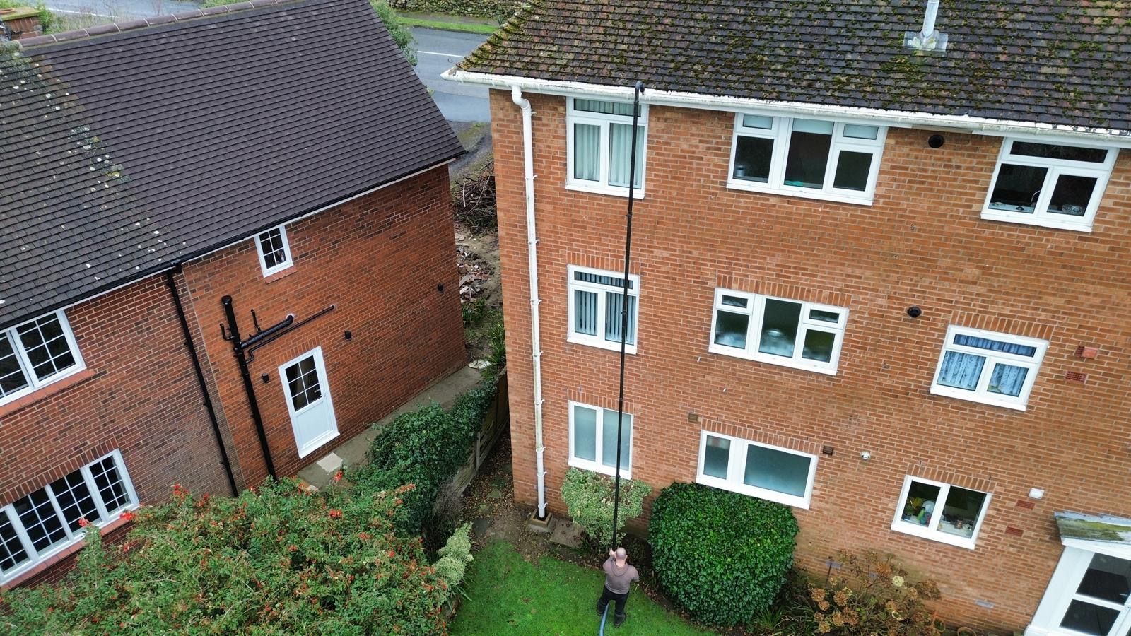 Two brick buildings with a narrow space in between, person standing in the yard below.