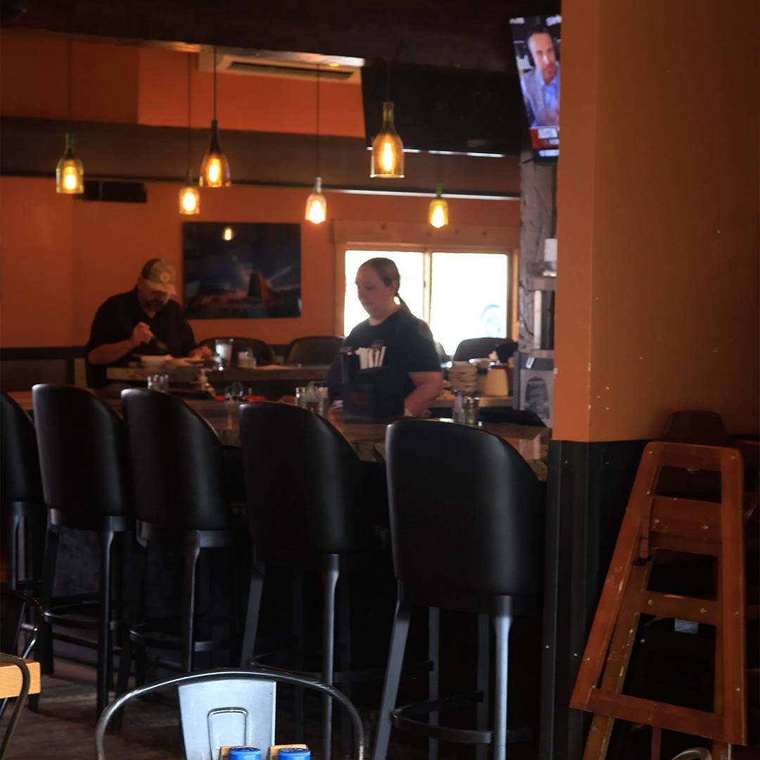 The cozy interior of The Back 40 restaurant featuring large picture windows that frame a panoramic view of the Heber Valley pastures and mountains.