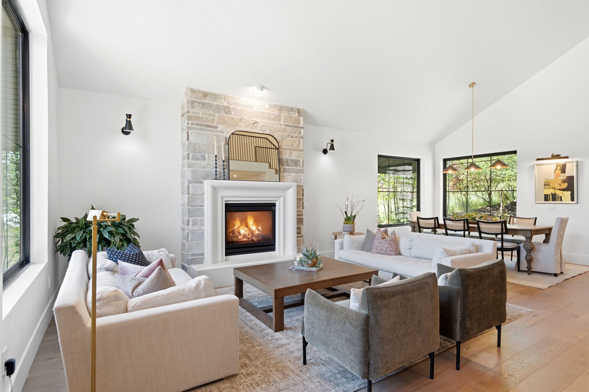 Vaulted great room featuring a stunning floor-to-ceiling stone fireplace and wide-plank hardwood floors.
