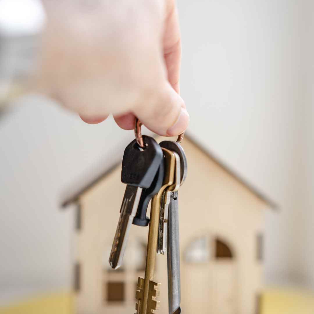 A homebuyer holding house keys with a new property in the background, representing a successful real estate purchase in the Park City housing market.