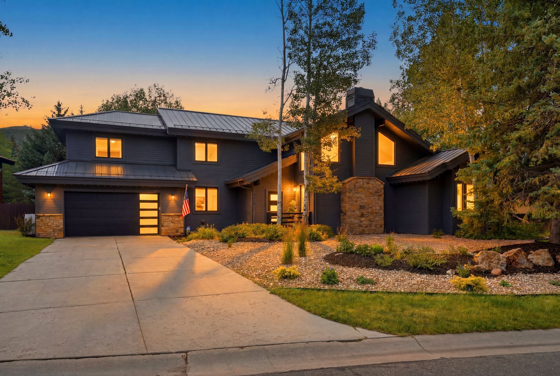 Twilight exterior view of the remodeled 5172 E Meadows Drive estate in Silver Springs, Park City, featuring a modern dark facade and warm interior lighting.