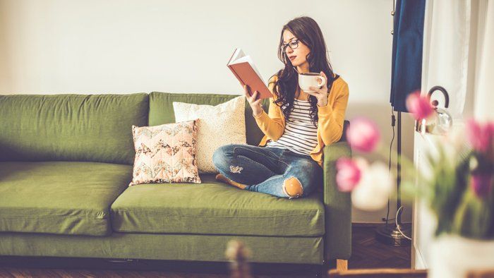 girl reading a book on a green couch