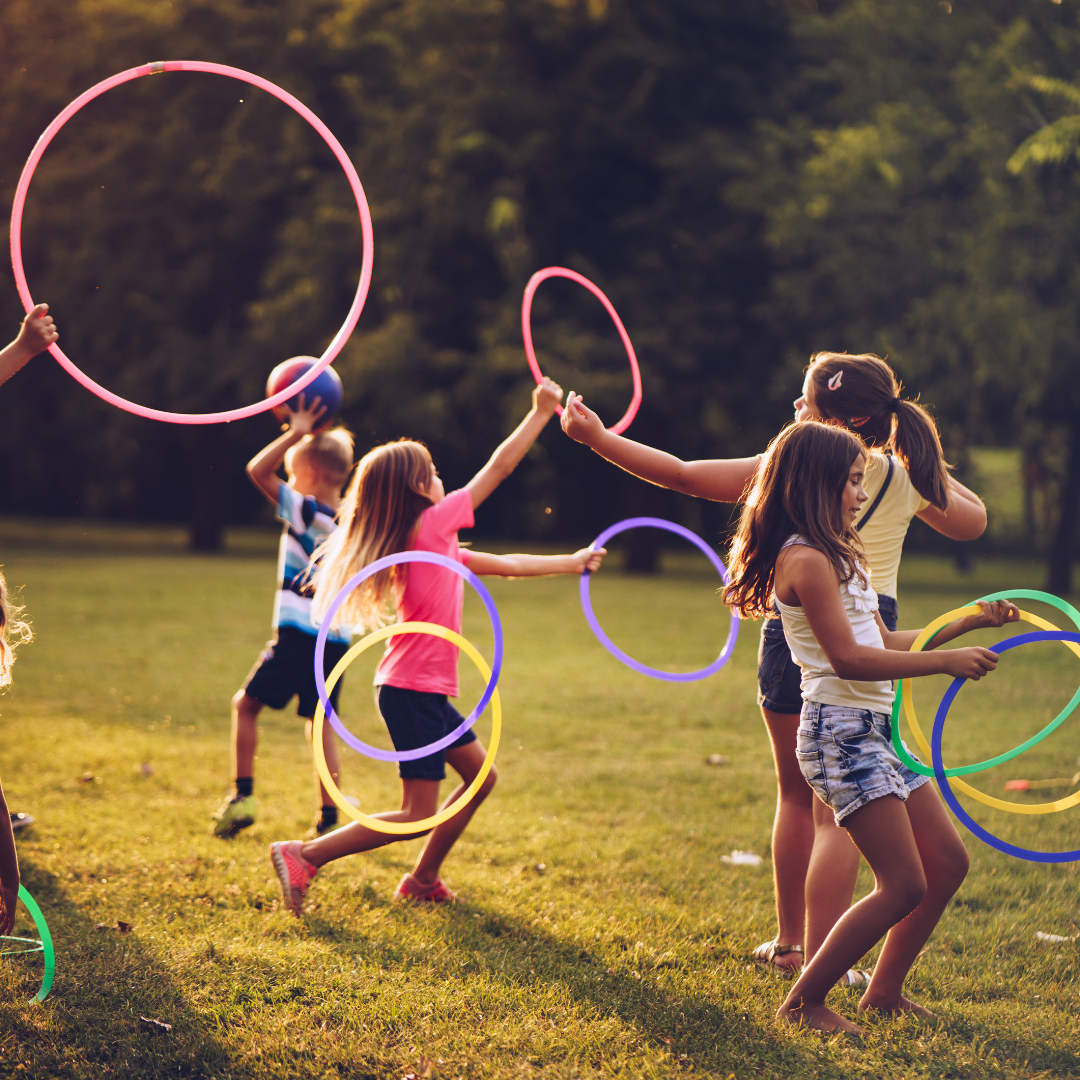 A group of children are playing with hula hoops in a park