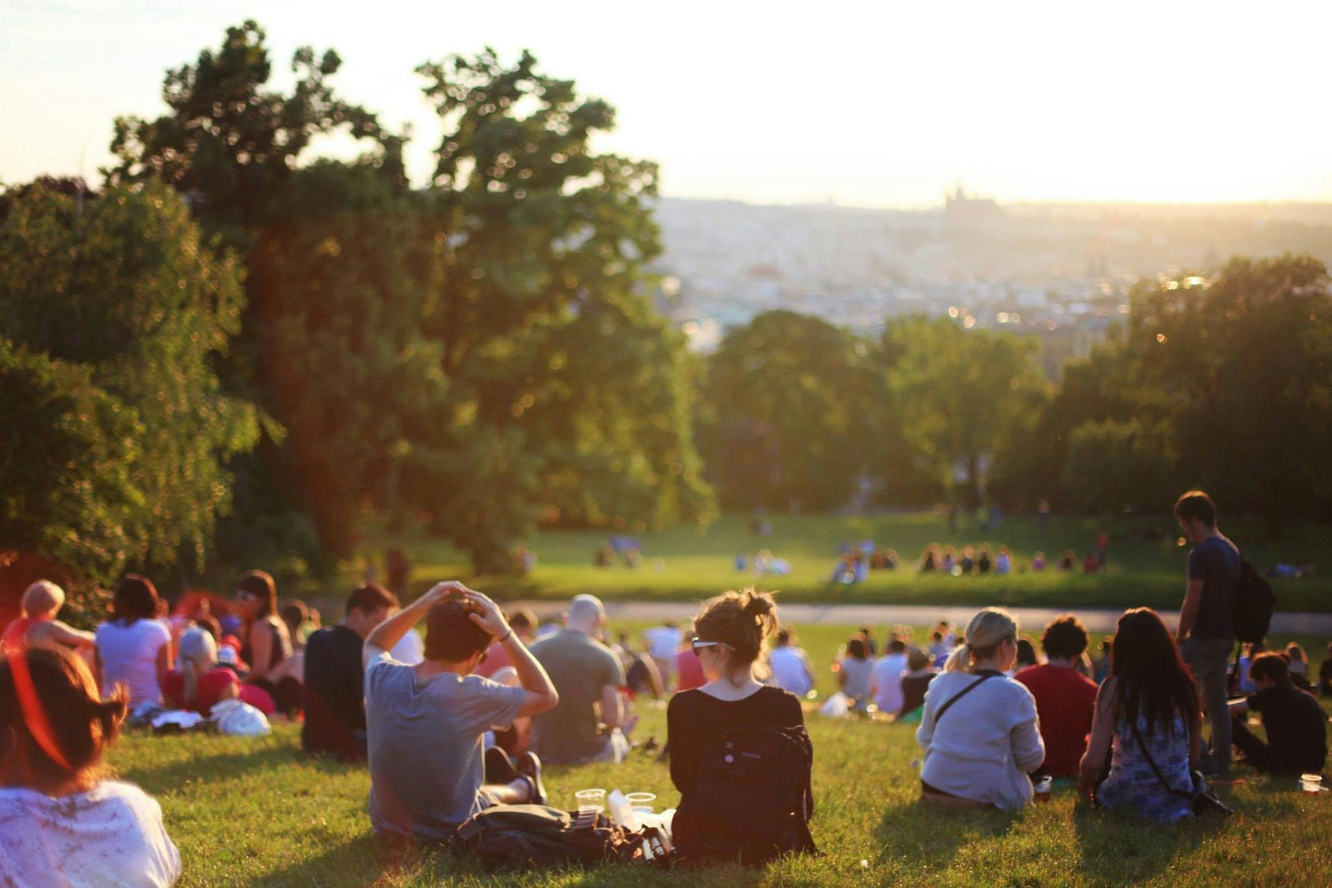 A group of people are sitting on the grass in a park.