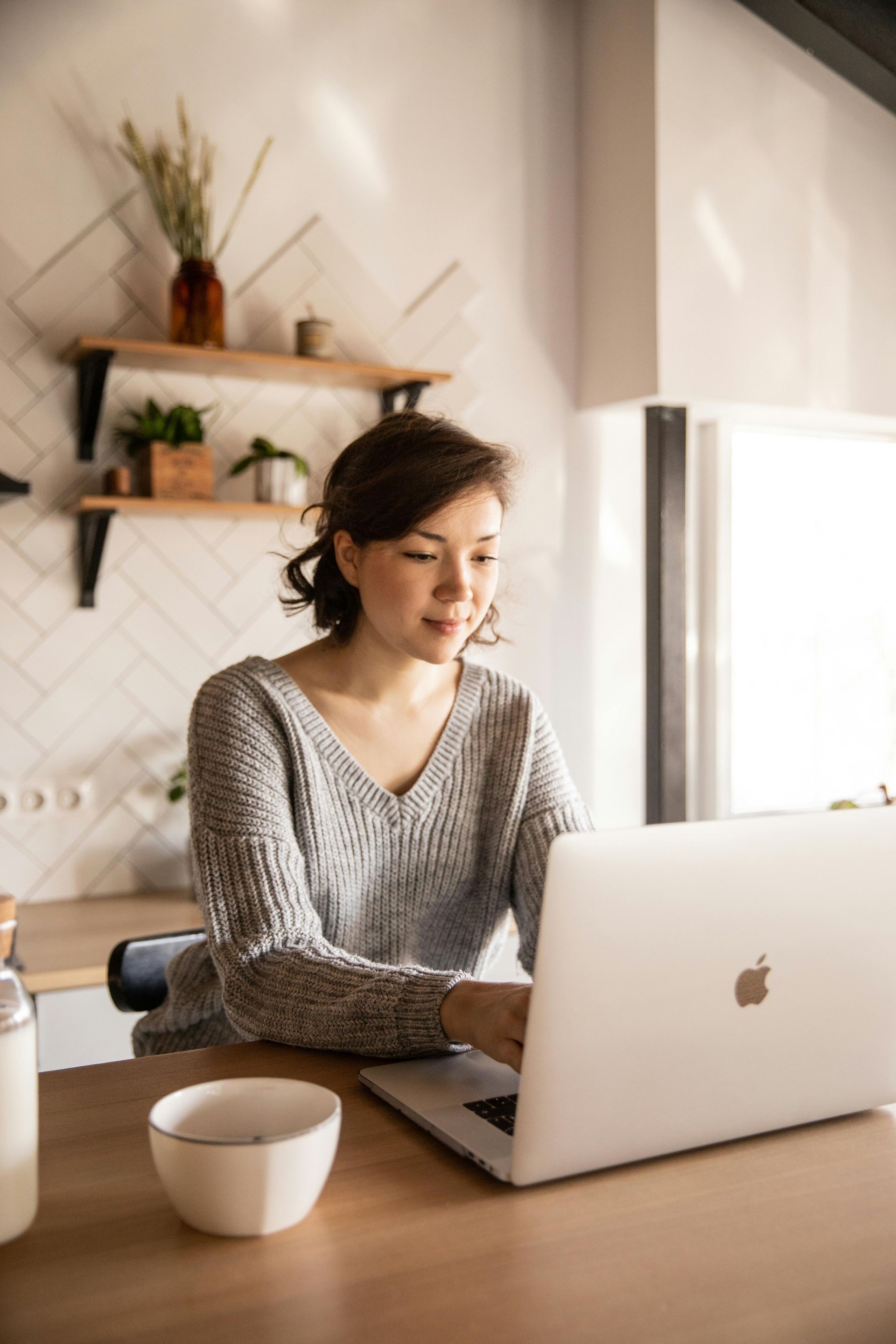 A woman is sitting at a table using a laptop computer.