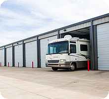 RV parked in an open storage unit at a facility with multiple bays.
