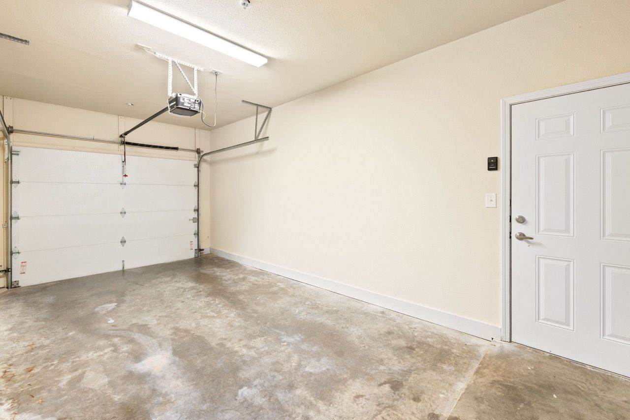 Interior of a residential garage with a white roll-up door and concrete floor