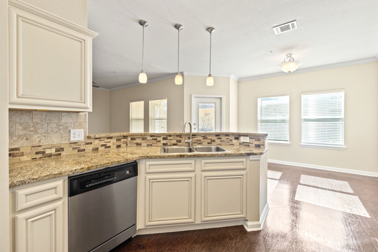 Bright kitchen with granite counters, double sink, and stainless-steel appliances.
