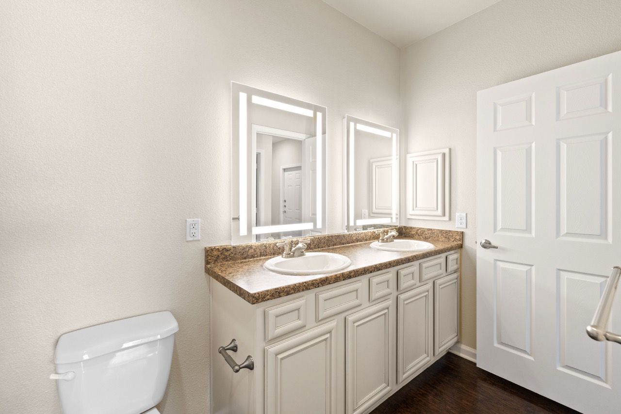 Bathroom with a double-sink vanity, granite countertop, and a toilet.