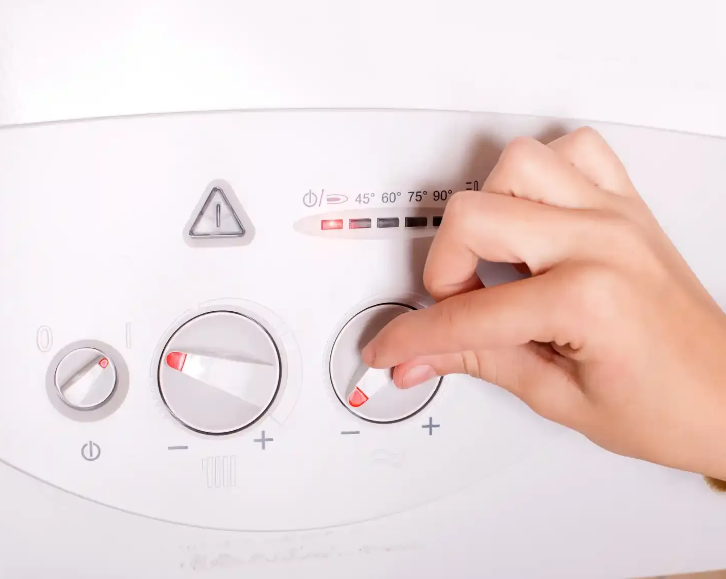 Mano che regola una manopola su un pannello di controllo bianco, probabilmente per un sistema di riscaldamento.