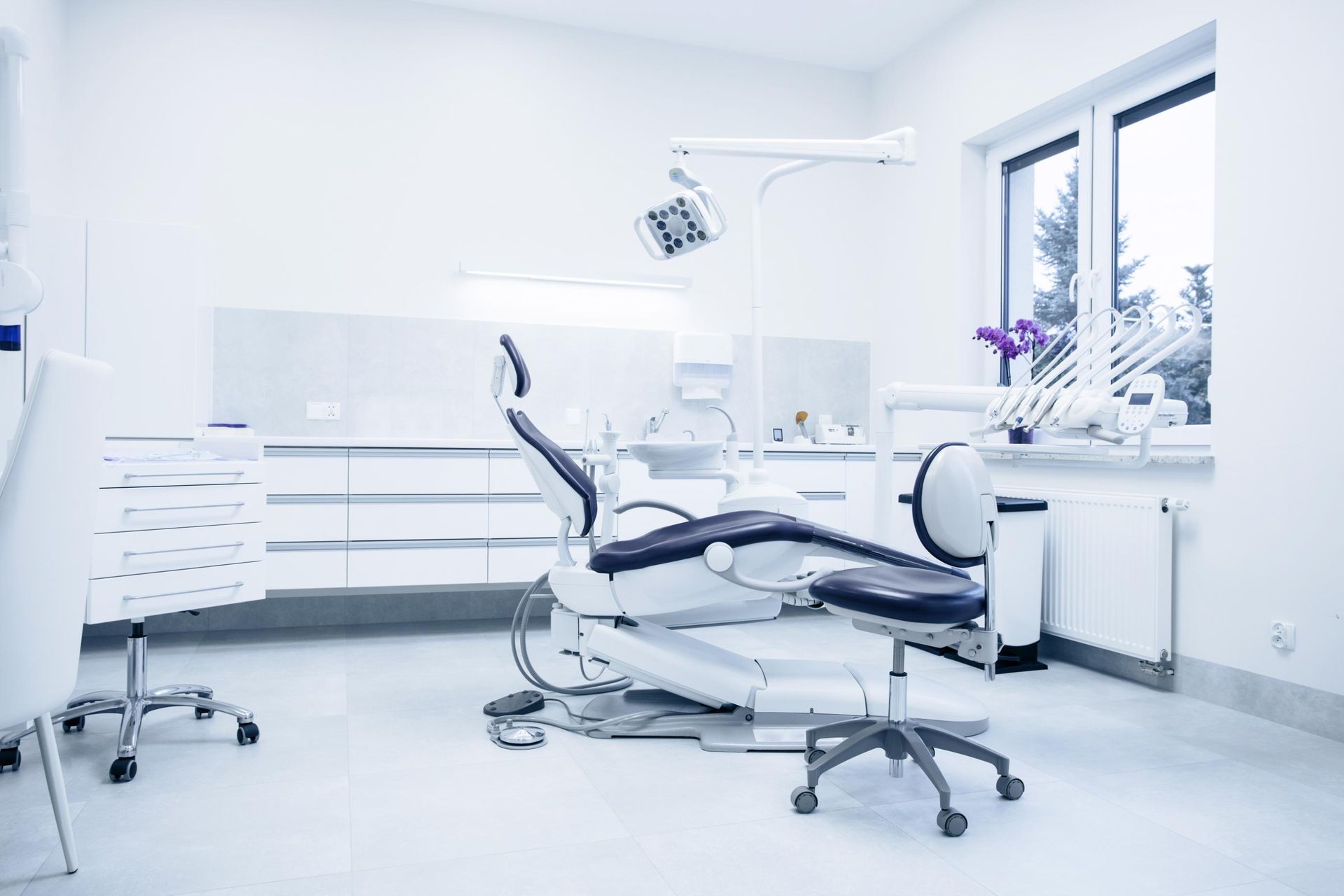 Dental examination room with chair, equipment, and window.