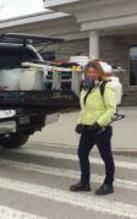 A woman in a yellow jacket is standing in front of a truck.