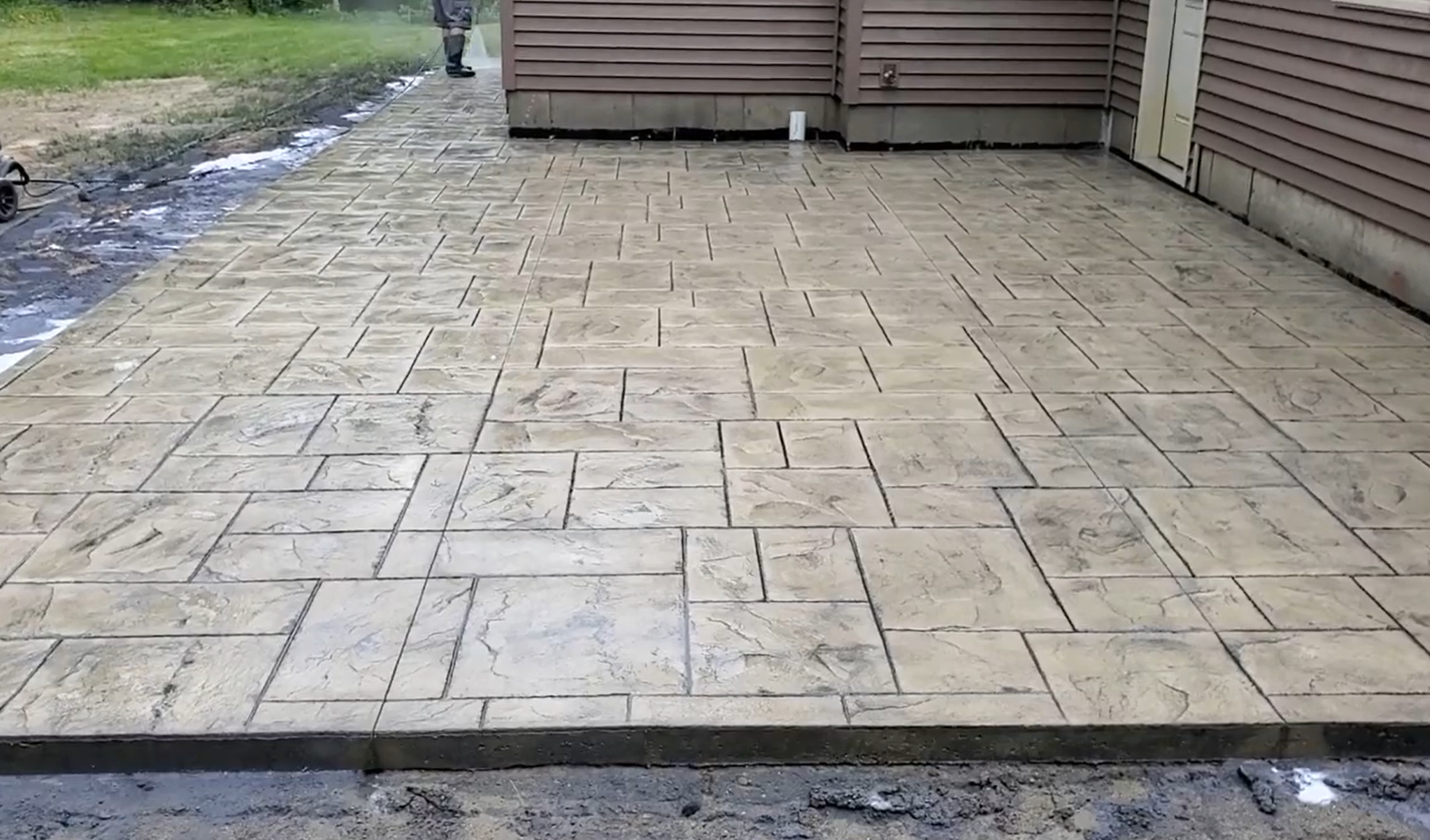 Crew member sealing after concrete patio stamped and stained.
