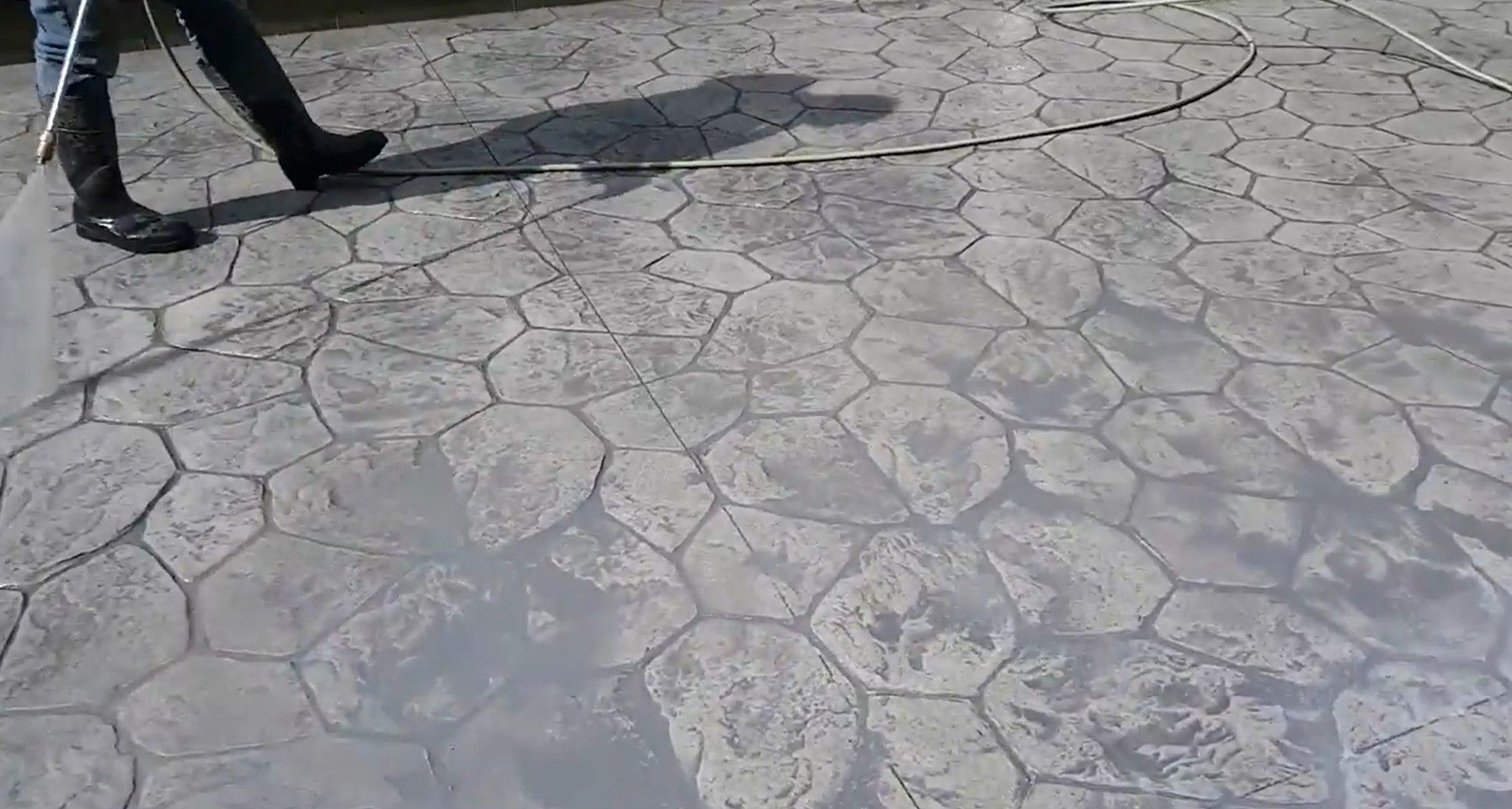 Man staining stamped concrete patio.