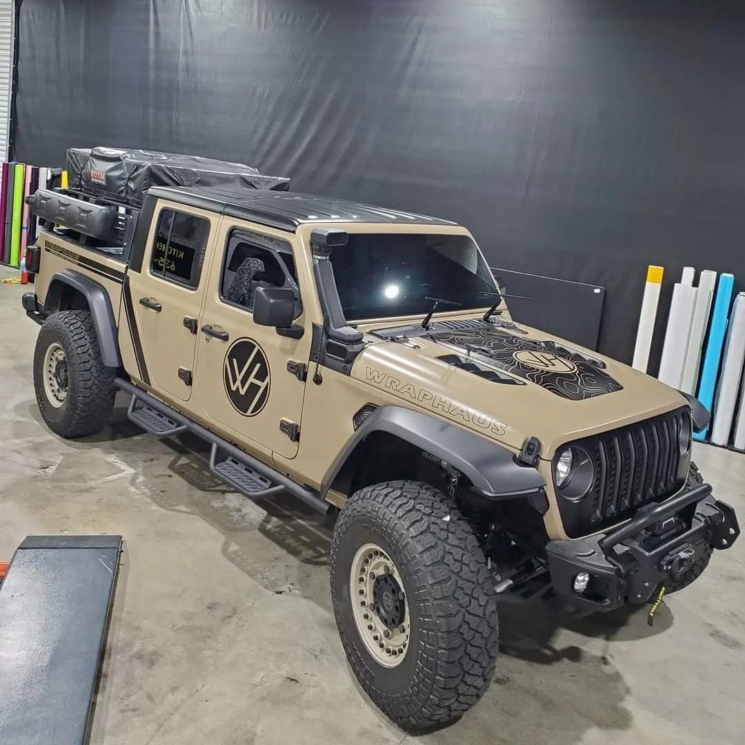 A tan jeep is parked in a garage.
