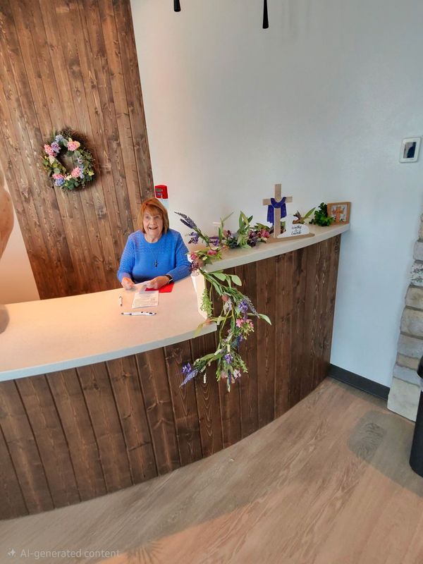 Large group of people standing in a church. A cross hangs on the wall, and colored light shines.