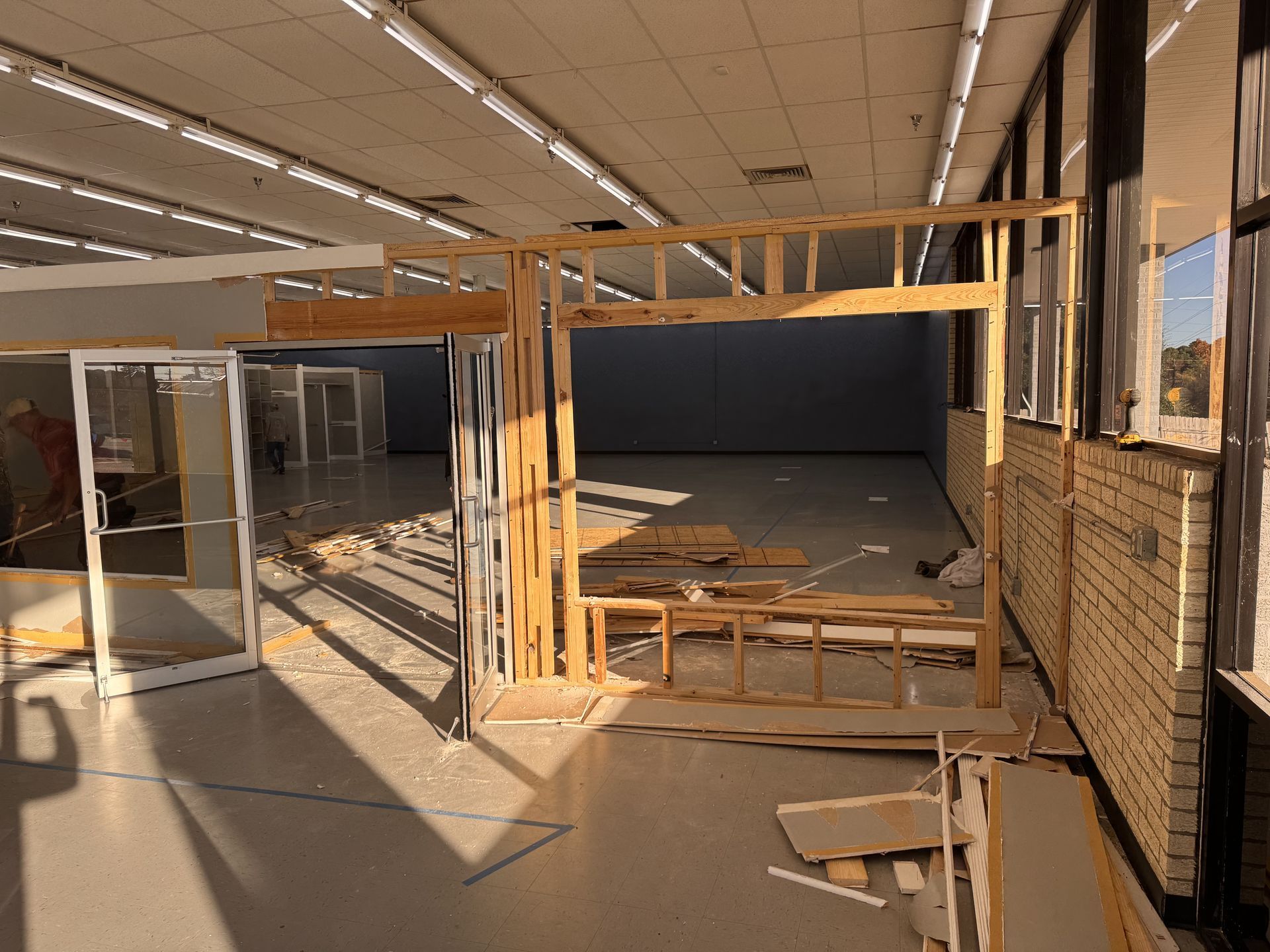 Interior construction site with exposed wooden framing and brick wall.