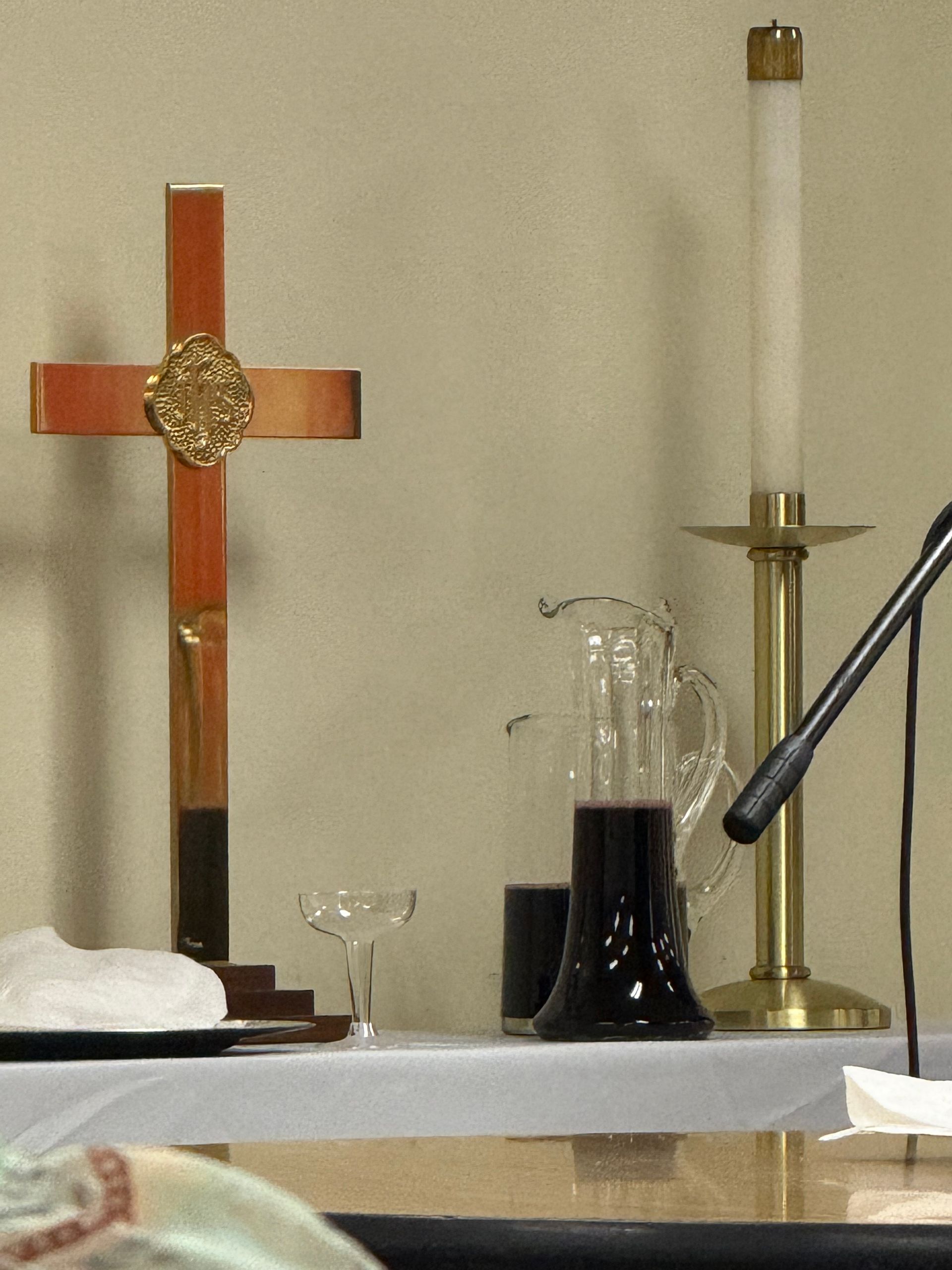 Altar with a cross, candle, wine, bread, and microphone, likely for a religious service.