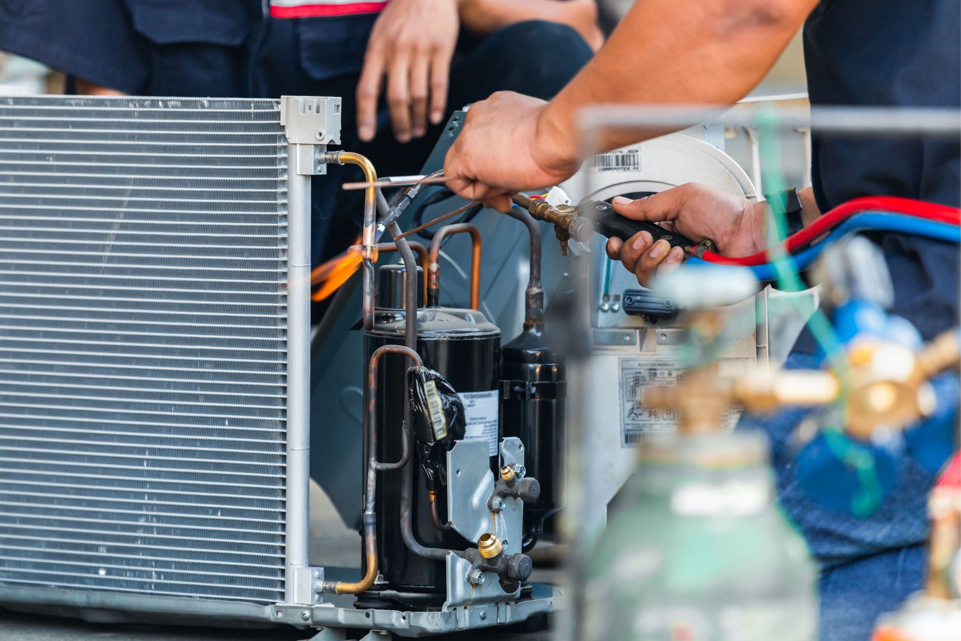 A man is working on an air conditioner with a wrench.