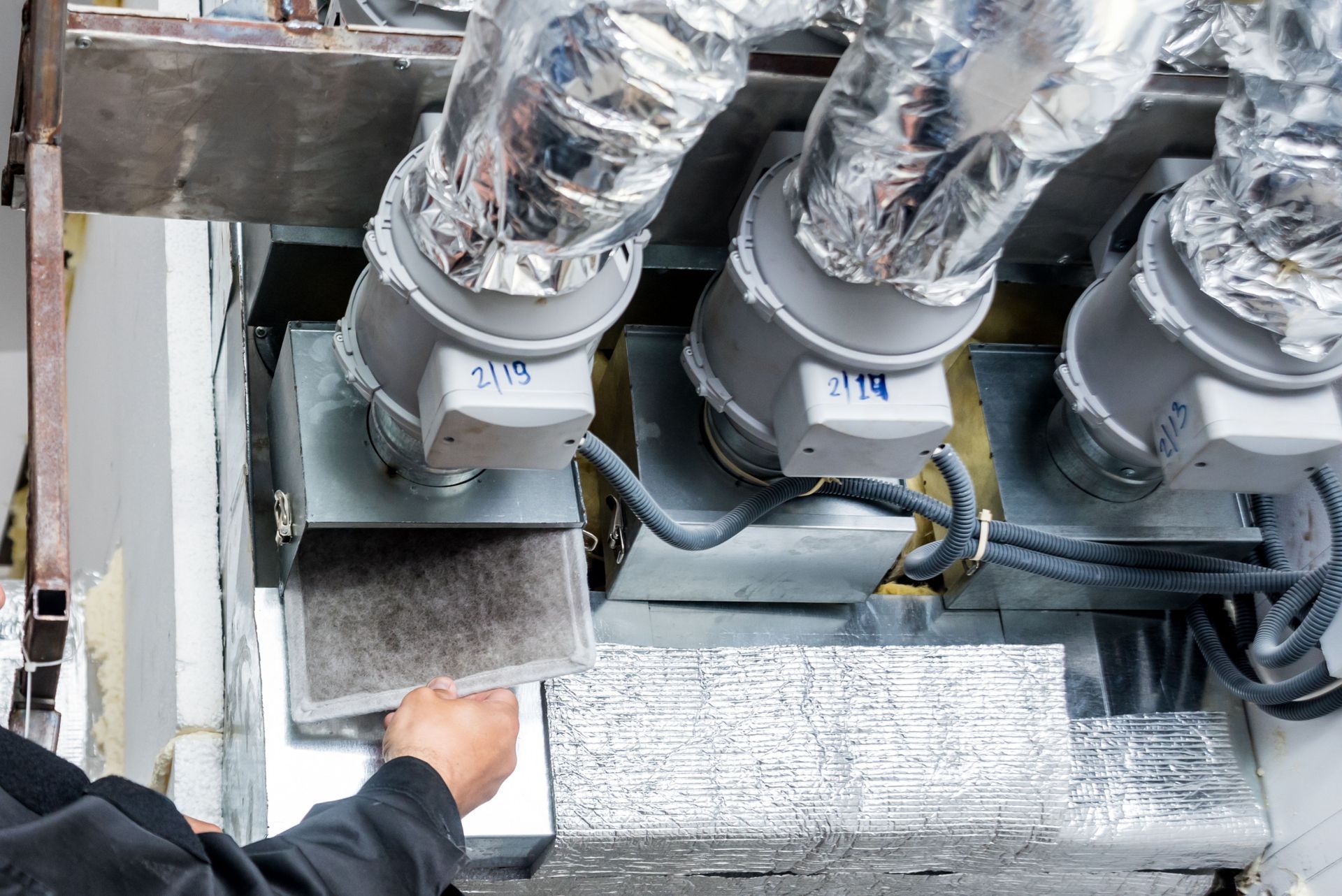 A man is working on a ventilation system in a building.