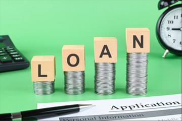 “Loan” word formed with wooden cubes on coin stack, symbolizing signature loan services. “Loan” word formed with wooden cubes on coin stack, symbolizing signature loan services.