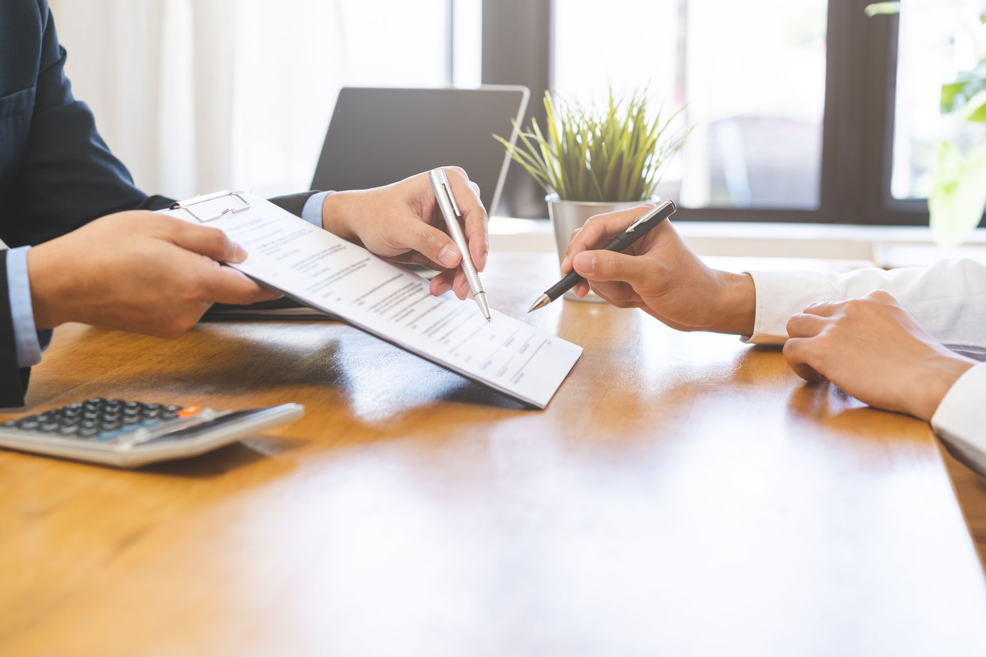 Person pointing at financial documents with a smartphone and a cup on a counter.
