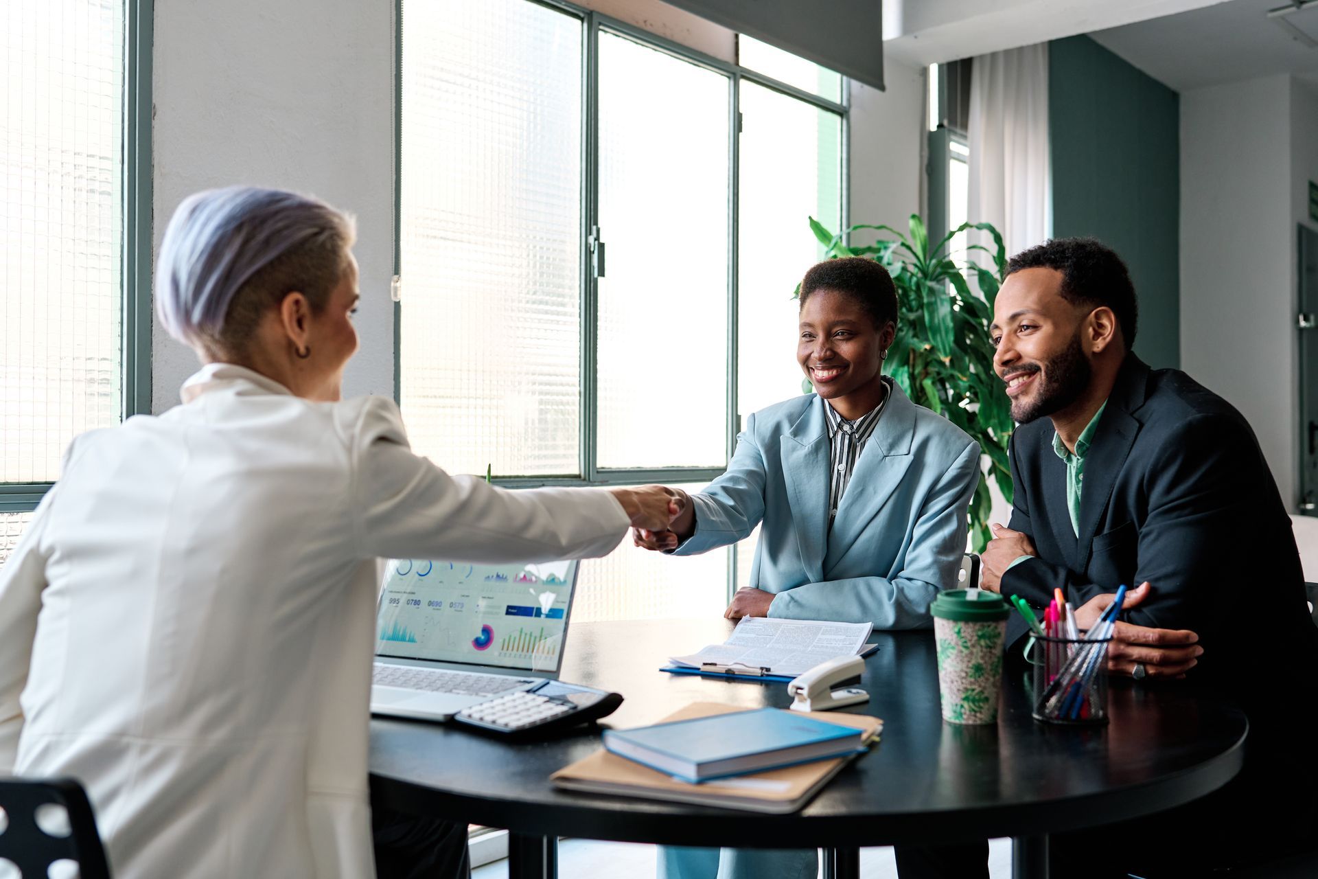 Personal Loan—Business meeting with handshake, documents on table in modern office setting.