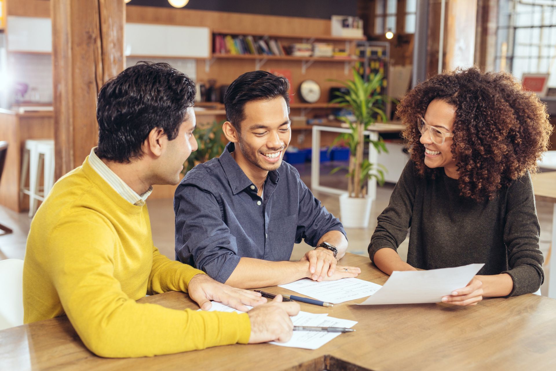 A Man and a Woman Showing a Man Between them Papers and Smiling in an Office