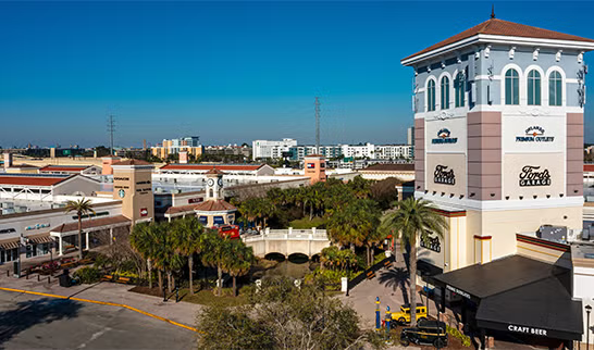 Aerial view of a shopping center with a tall white tower under a clear blue sky