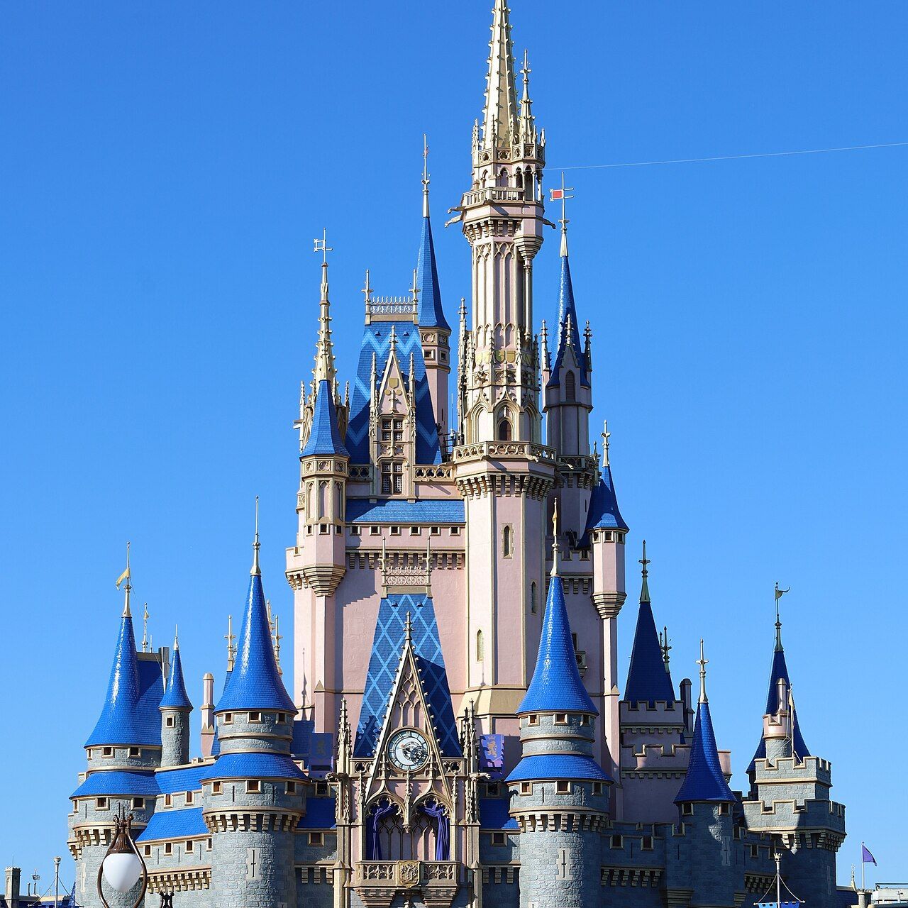 Cinderella Castle with blue roofs and a tall central spire against a clear blue sky