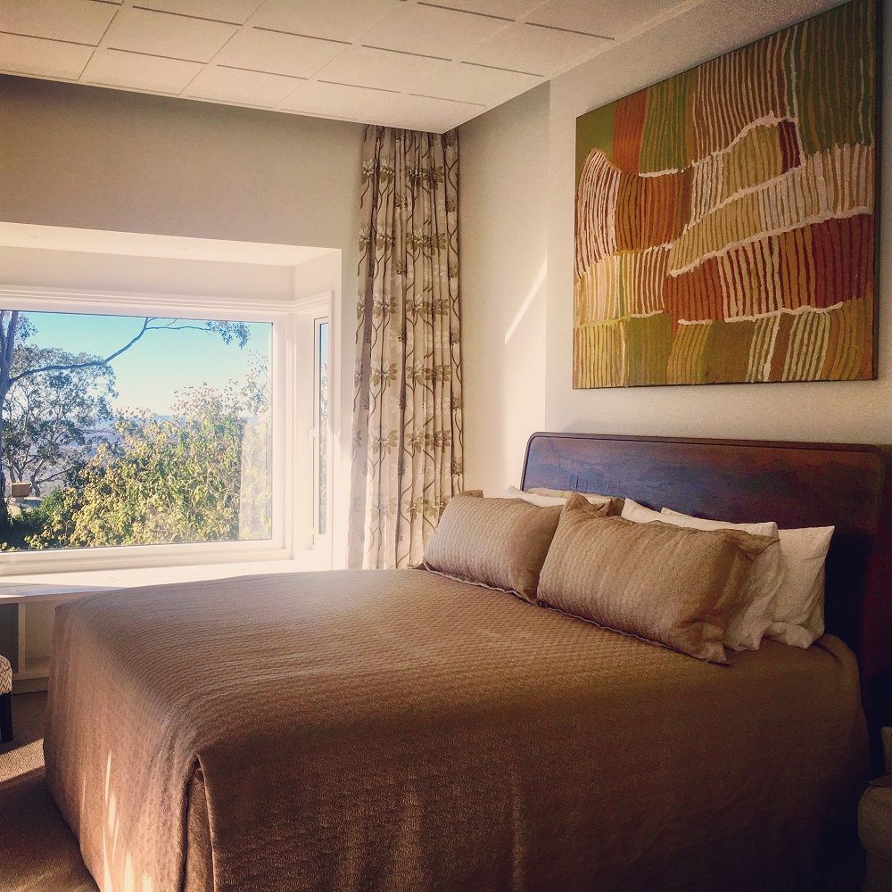 A bedroom with an indigenous artwork, hung by the ARTHOP Toowoomba experts.