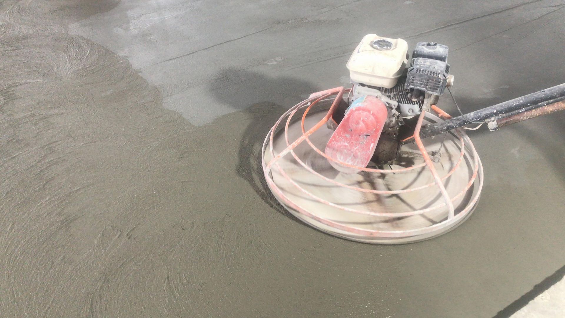 Power trowel smoothing wet concrete surface during construction. Power trowel smoothing wet concrete surface during construction.