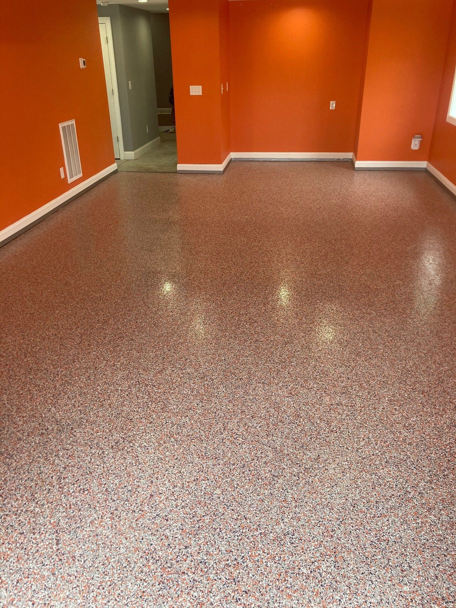 Orange-painted room with a speckled red and white epoxy floor