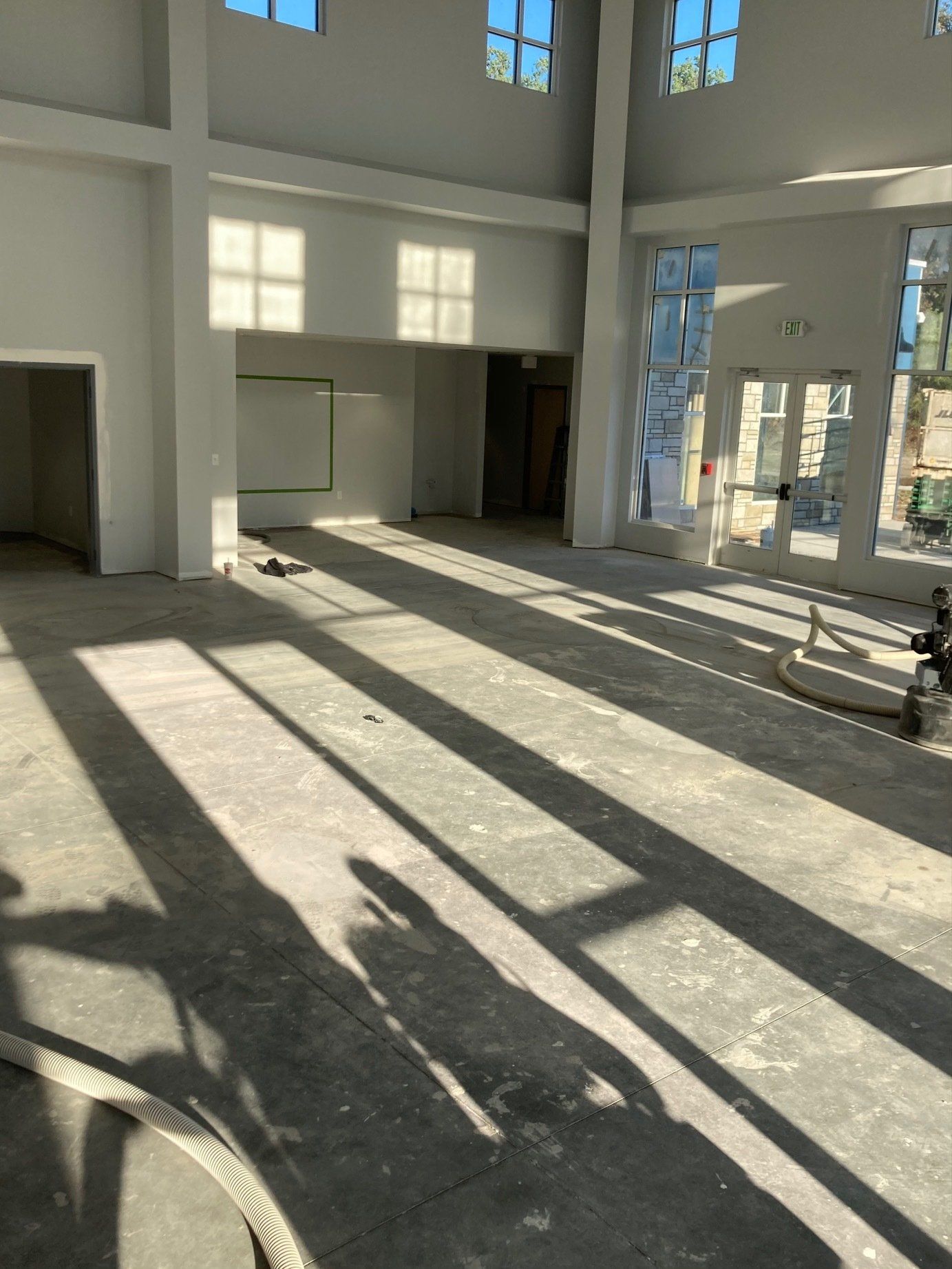 Interior of a brightly lit, empty room with long shadows from windows.